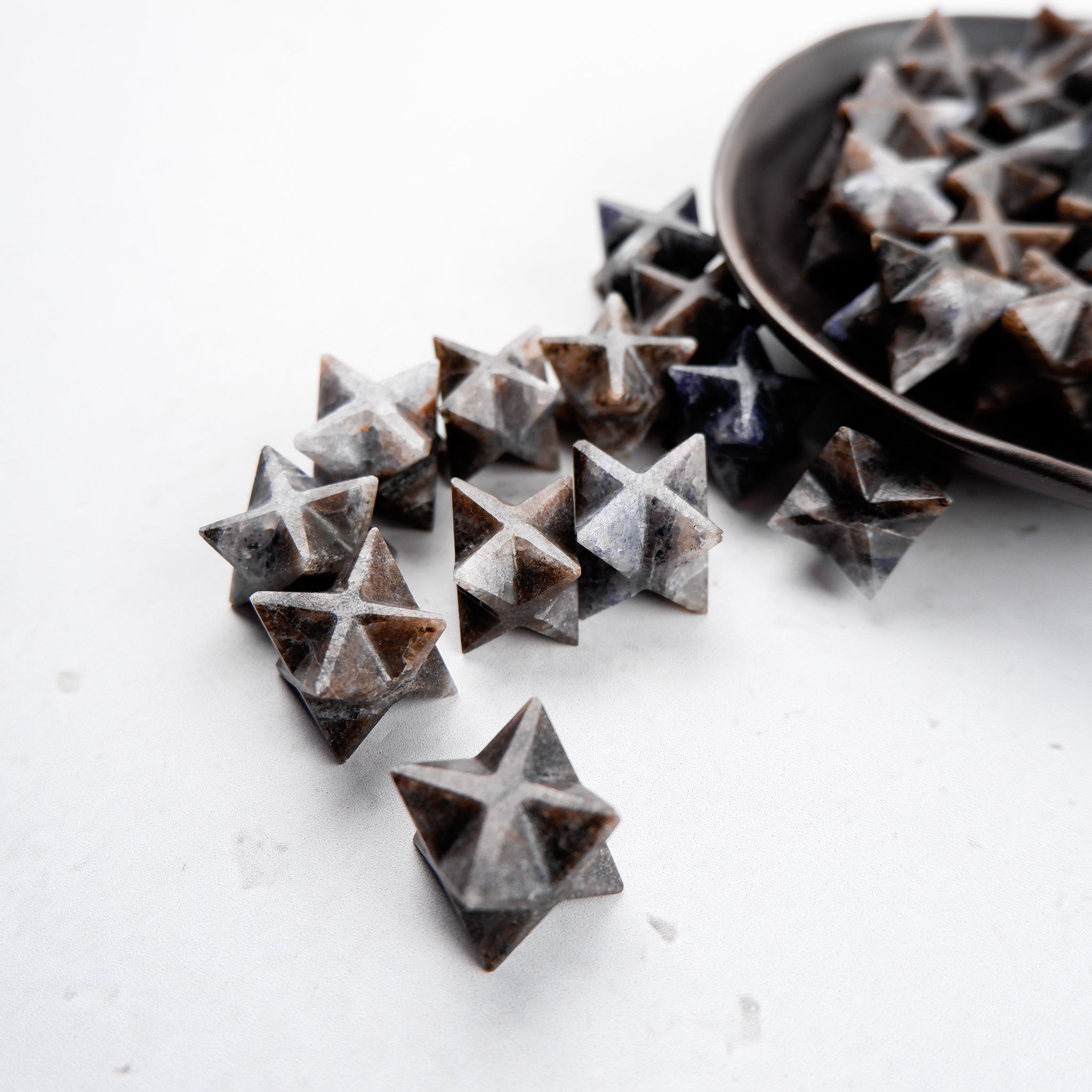 Iolite Star gemstone from Noctis Studio with a polished, star-shaped cut showcasing its vibrant blue color and intricate facets.