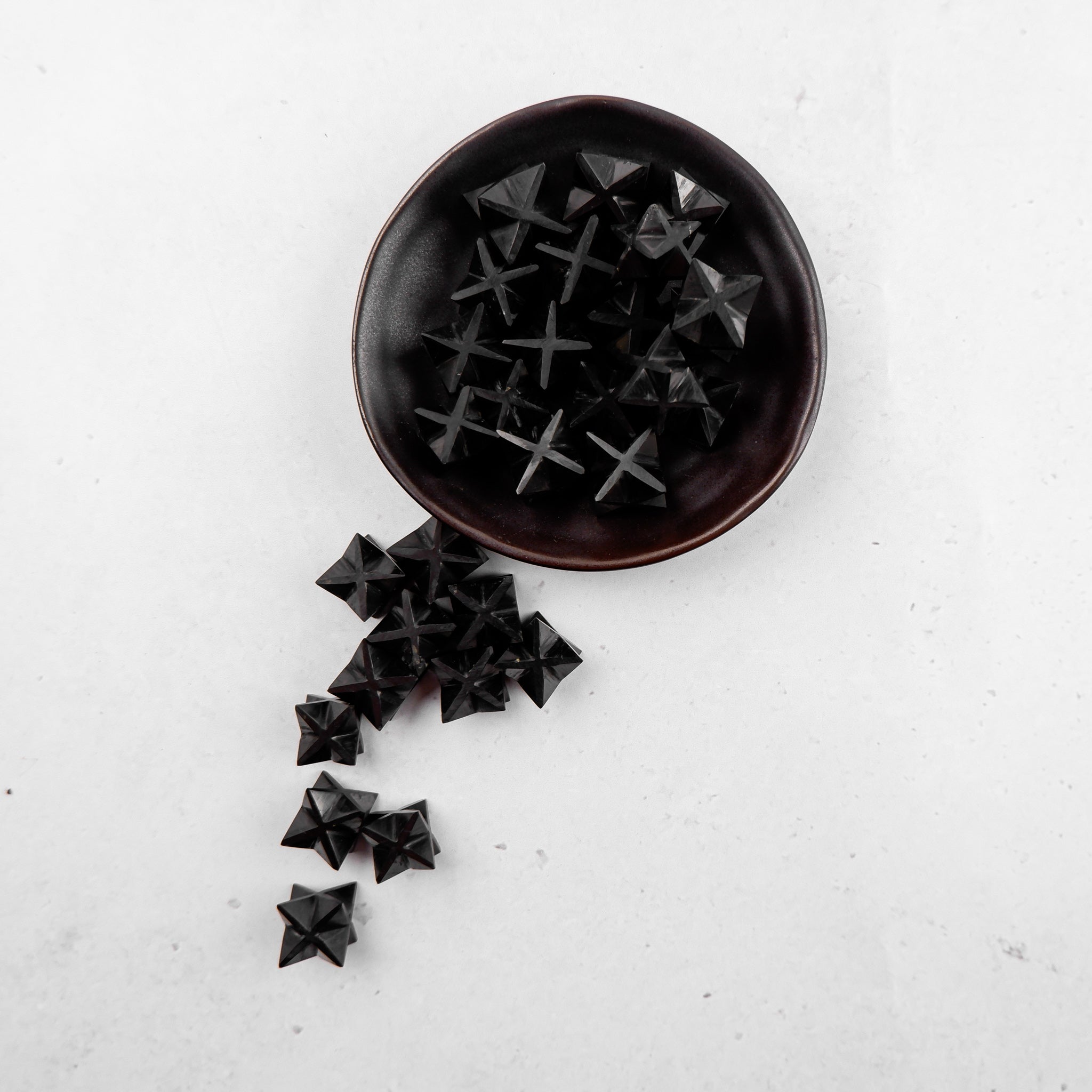 Shungite star pendant from Noctis Studio, showcasing a polished, star-shaped black mineral with natural shine and textured surface.