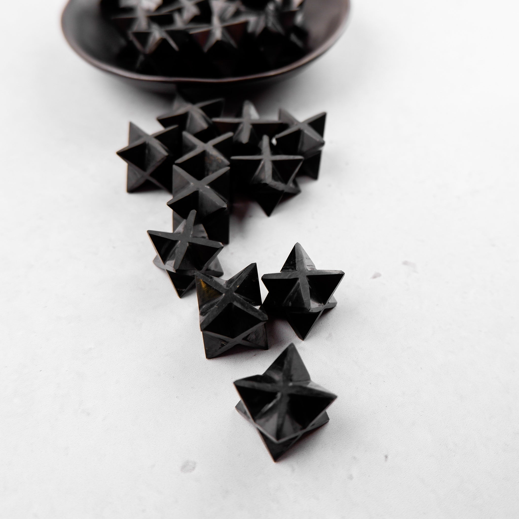 Shungite star pendant from Noctis Studio, featuring a polished black star-shaped mineral with natural textures and reflective surfaces.
